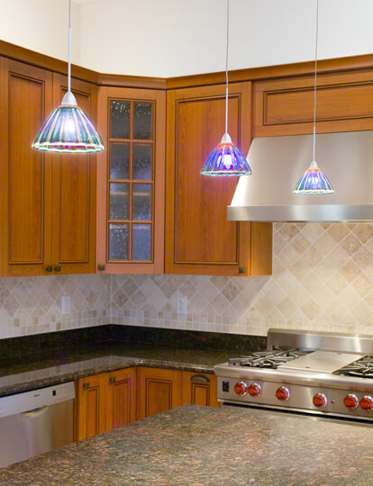 Remodeled kitchen with hanging lights over marble countertops