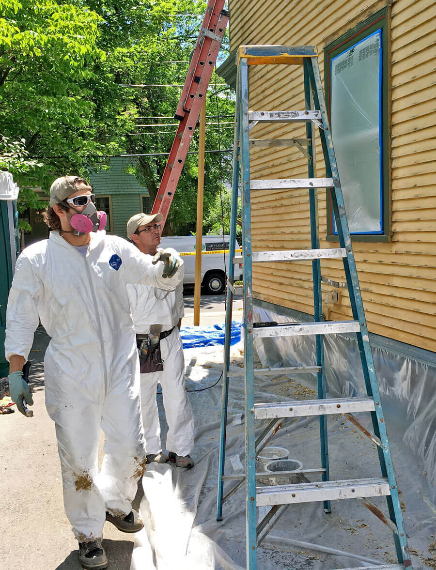 Painters following lead safety precautions while working on the side of a house