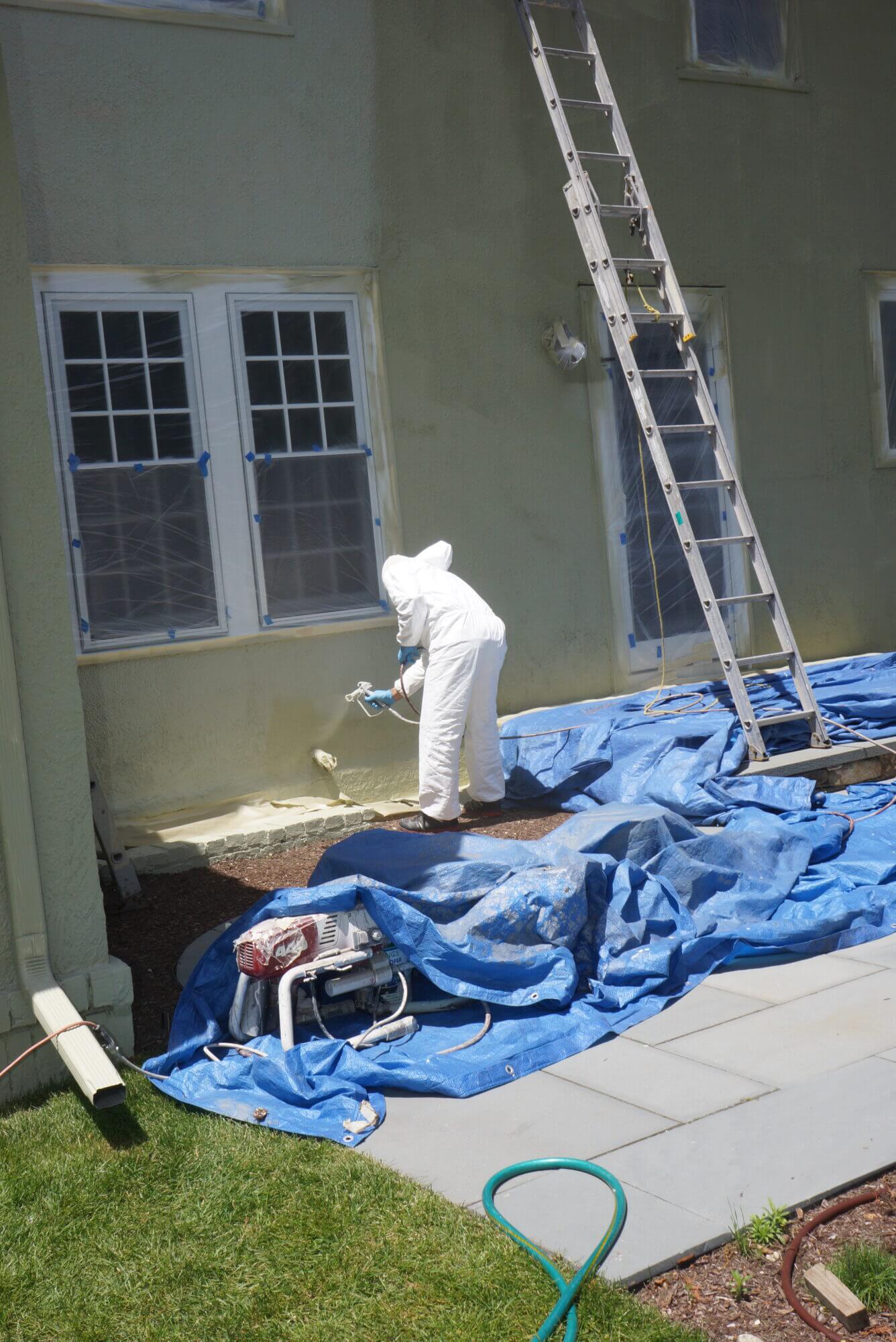 Catchlight employee applying paint to exterior of wall on home