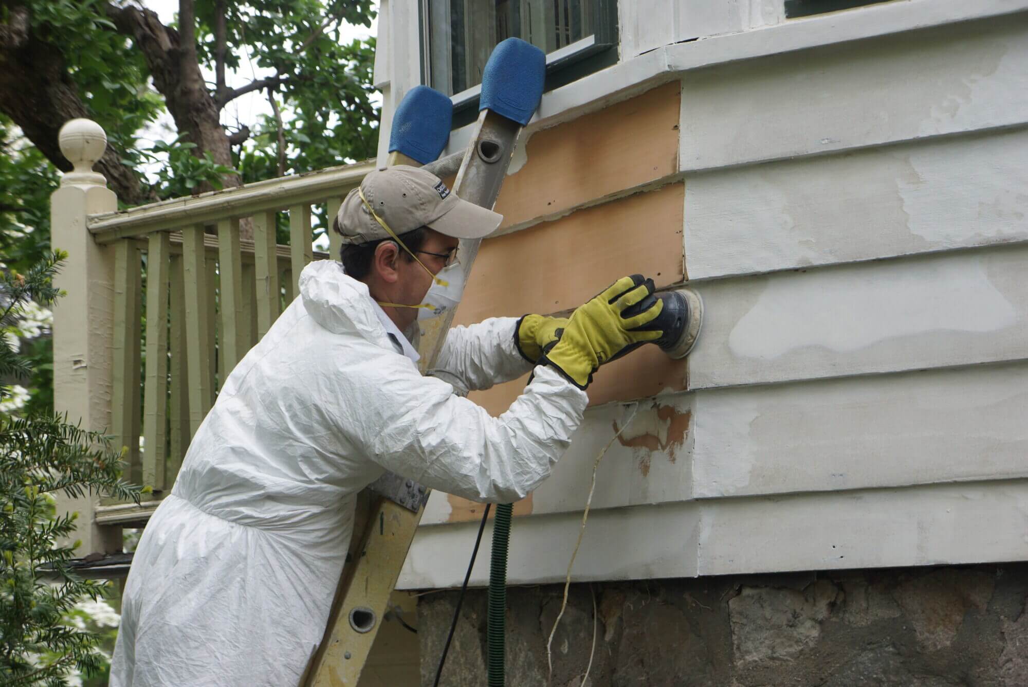 employee using a sander on home exterior